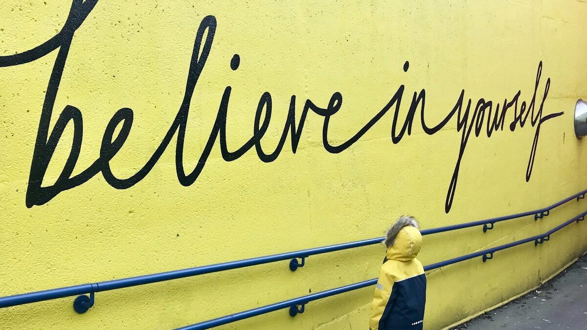 toddler looking at believe in yourself graffiti